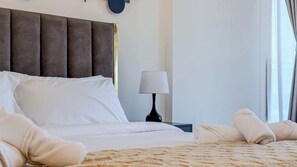 A hotel room with a large bed, a bedside table with a lamp, and a view of the outdoors through the window. - Full Burj Khalifa View, Central Dubai, Furnished (Dubai)
