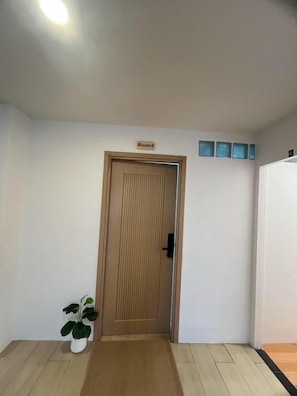 Una habitación con puerta de madera, una planta pequeña en maceta y un cartel que indica 'Room 3'.
