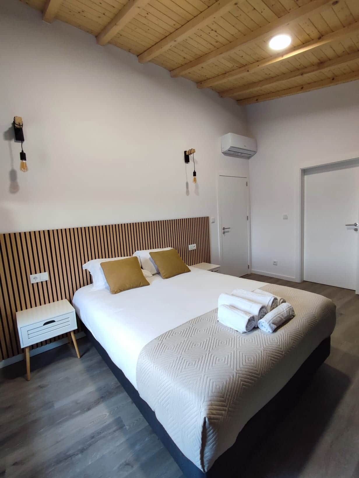 Una habitación de hotel con una cama grande, una mesita de noche, un armario y una lámpara en el techo.