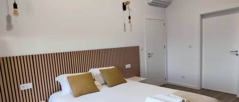Una habitación de hotel con una cama grande, una mesita de noche, un armario y una lámpara en el techo.