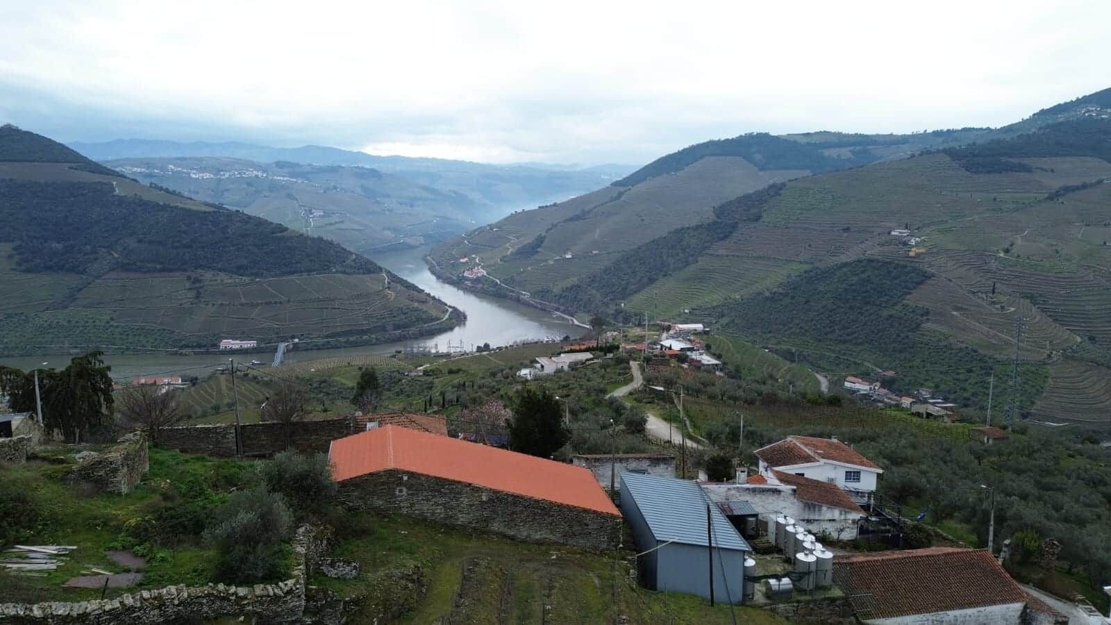 Un paisaje rural con campos escalonados, un río y edificios dispersos.
