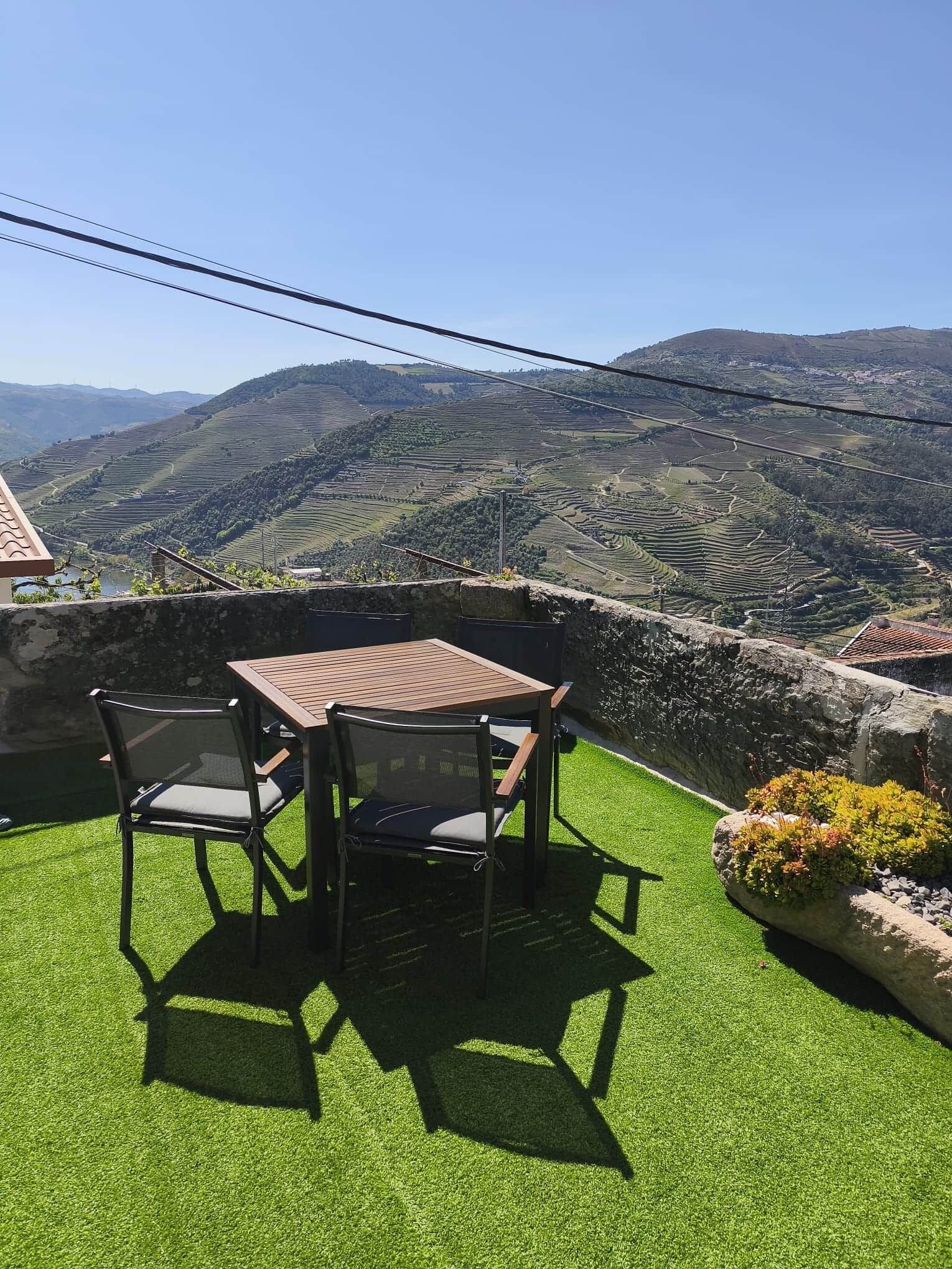 Una terraza con mesa y sillas, con vistas a campos escalonados y colinas.