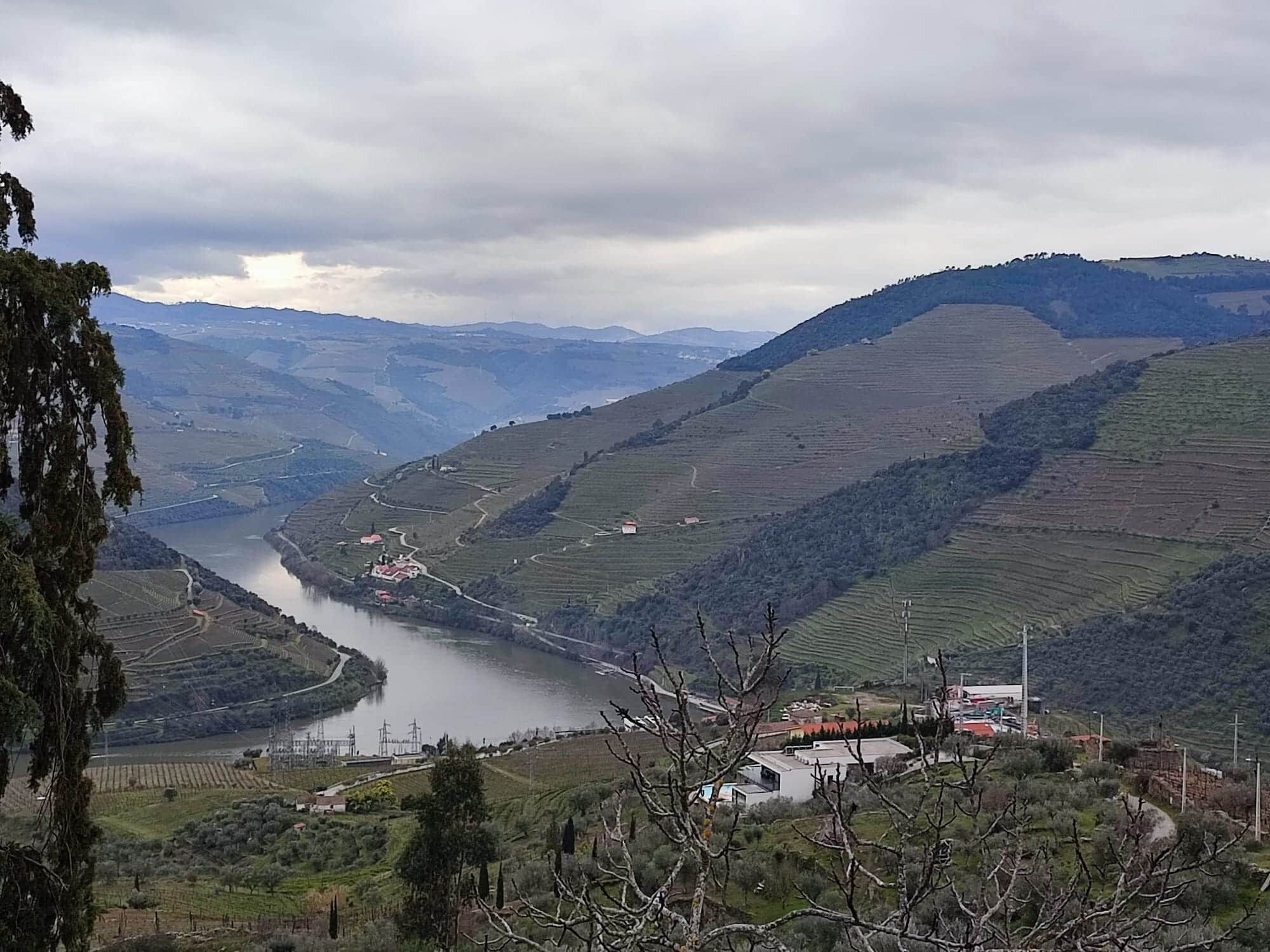 Un río serpentea a través de campos en terrazas con un pequeño asentamiento y algunos edificios a lo largo de la orilla.