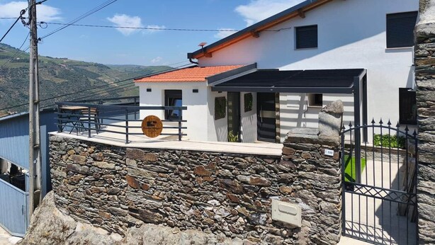 A modern two-story building with a stone facade, a red-tiled roof, and a sign indicating a restaurant. - Castas D'ouro Guest House II (Casal de Loivos)