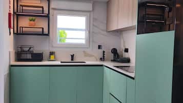 Una cocina con gabinetes color turquesa, un ventanal y un horno empotrado.