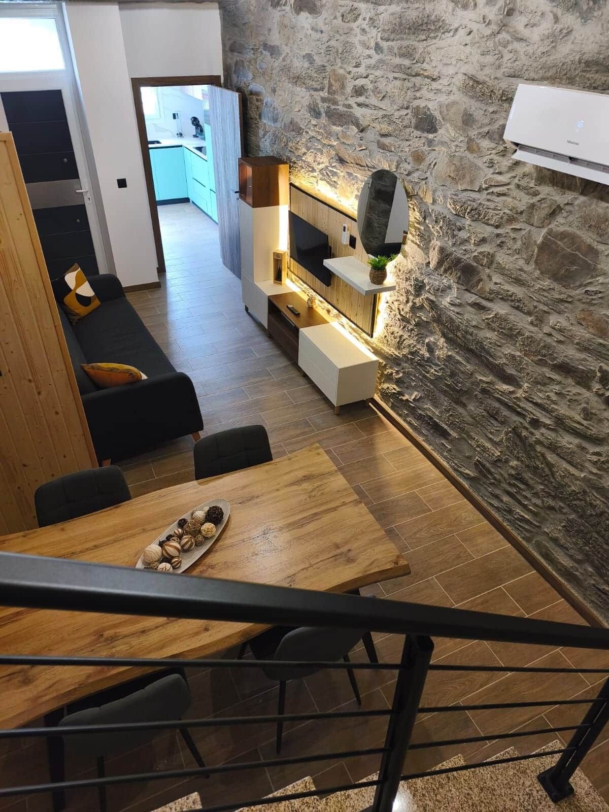 Eine moderne Küche mit Steinwand, Holzschränken und einem Essbereich mit Holztisch und Stühlen.