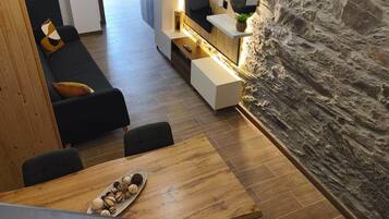 Eine moderne Küche mit Steinwand, Holzschränken und einem Essbereich mit Holztisch und Stühlen.