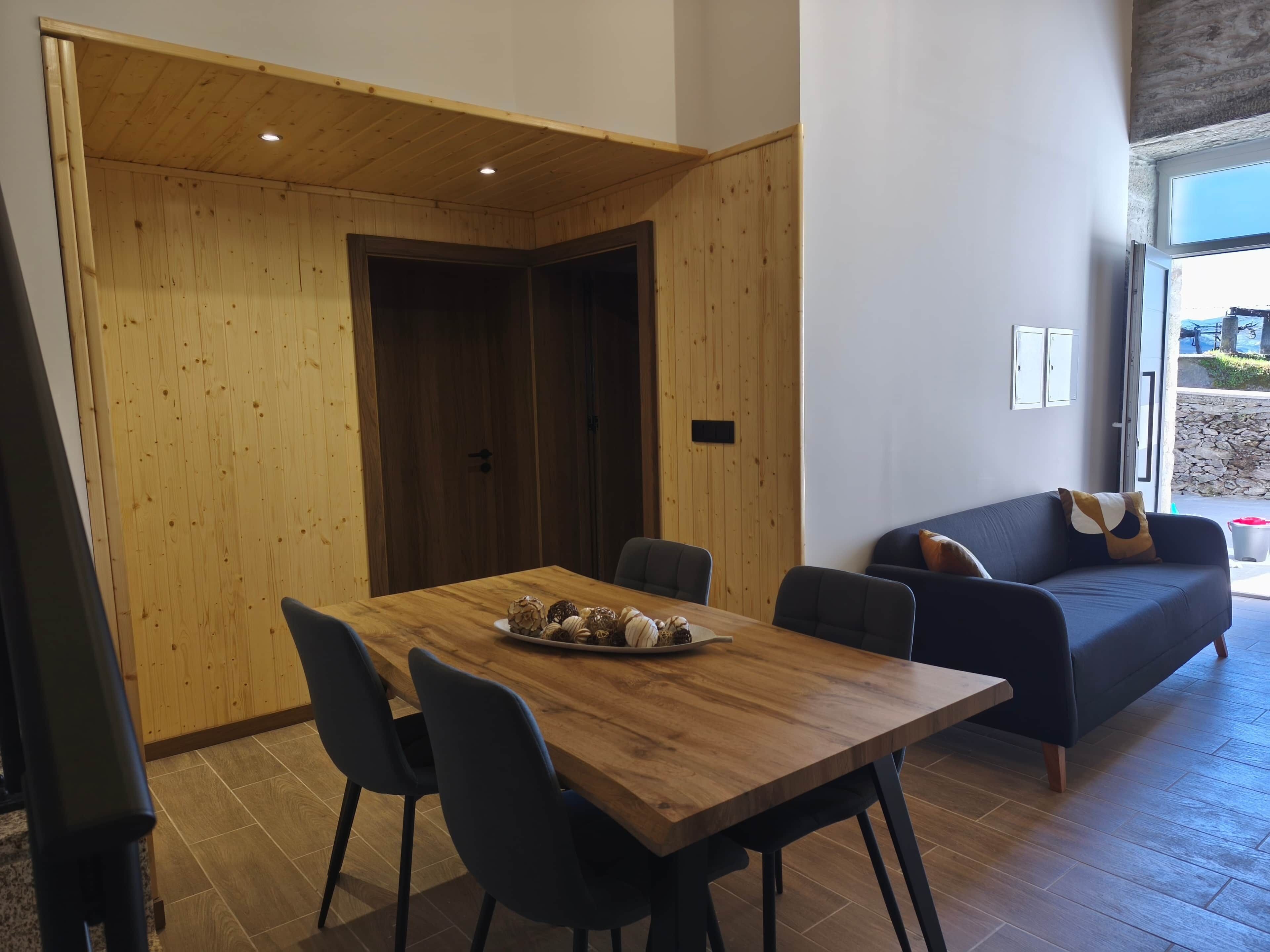 Un intérieur moderne avec une table à manger en bois, des chaises et un canapé de couleur foncée.