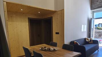 Un intérieur moderne avec une table à manger en bois, des chaises et un canapé de couleur foncée.