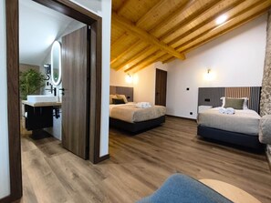 A modern bedroom with two beds, a wooden ceiling, and a bathroom with a sink and mirror. - Castas D'ouro Guest House II (Casal de Loivos)