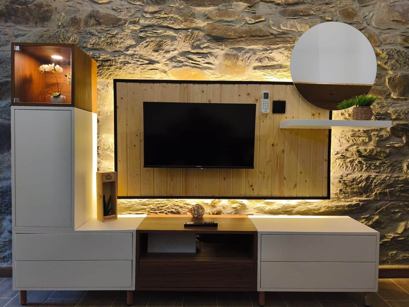 A modern entertainment unit with a flat-screen TV, wooden paneling, and built-in shelving.