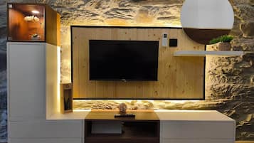 A modern entertainment unit with a flat-screen TV, wooden paneling, and built-in shelving.