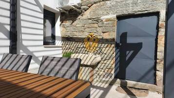 An outdoor seating area with a table and chairs, a stone wall, and a door.