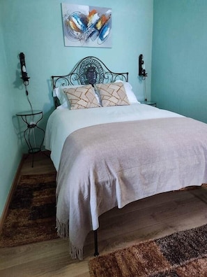 Una cama con un cojín estampado, una mesita de noche y una obra de arte colgada en la pared.