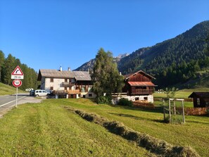 Eine Landstraße mit Geschwindigkeitsbegrenzungsschild, einem weißen Lieferwagen und traditionellen Gebäuden mit Holzdächern.