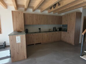 Eine moderne Küche mit Holzschränken, einem Einbauofen und einer Arbeitsplatte mit verschiedenen Geräten.