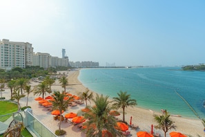 Een strandhotel met een zandstrand, palmbomen en een helder uitzicht op de zee.