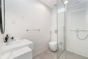 Een moderne badkamer met een douchecabine van glas, een witte wastafel en een toilet.