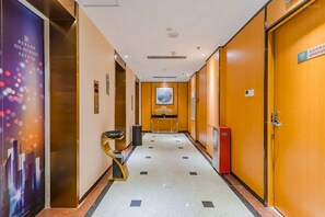A hotel corridor with a tiled floor, a reception desk, a framed artwork on the wall, and a door with a sign. - Borrman Hotel Pazhou Convention & Exhibition Center Branch, Sun Yat-sen University Station (Guangzhou)