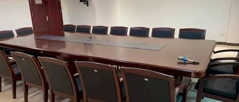 A conference room with a long table and chairs, a projector, and a door.