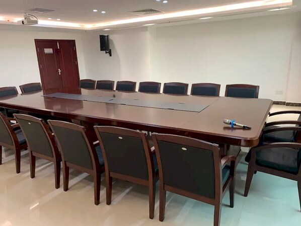 Un salón de conferencias con una larga mesa y sillas, un proyector y una puerta.