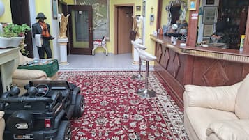 Eine Hotelhalle mit Rezeption, Essbereich, einer Kronleuchter und einem Spielzeugauto.