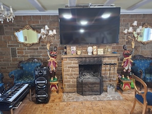 Una sala de estar con chimenea, televisor y piano.