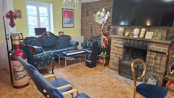 A living room with a sofa, chairs, a fireplace, a television, and a wine bottle.