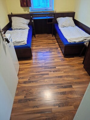 A compact room with two single beds, a small desk, and a window with curtains. - Vrbo Property (Wanzleben-Börde)
