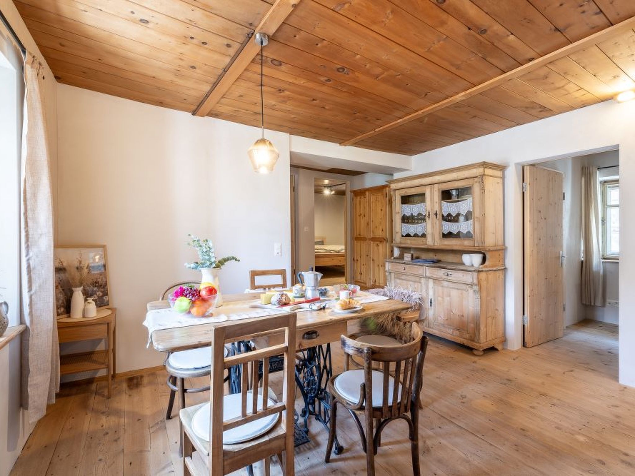 Un comedor con una mesa de madera, sillas y una lámpara colgante.