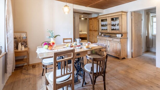 A dining area with a wooden table, chairs, and a hanging light fixture.