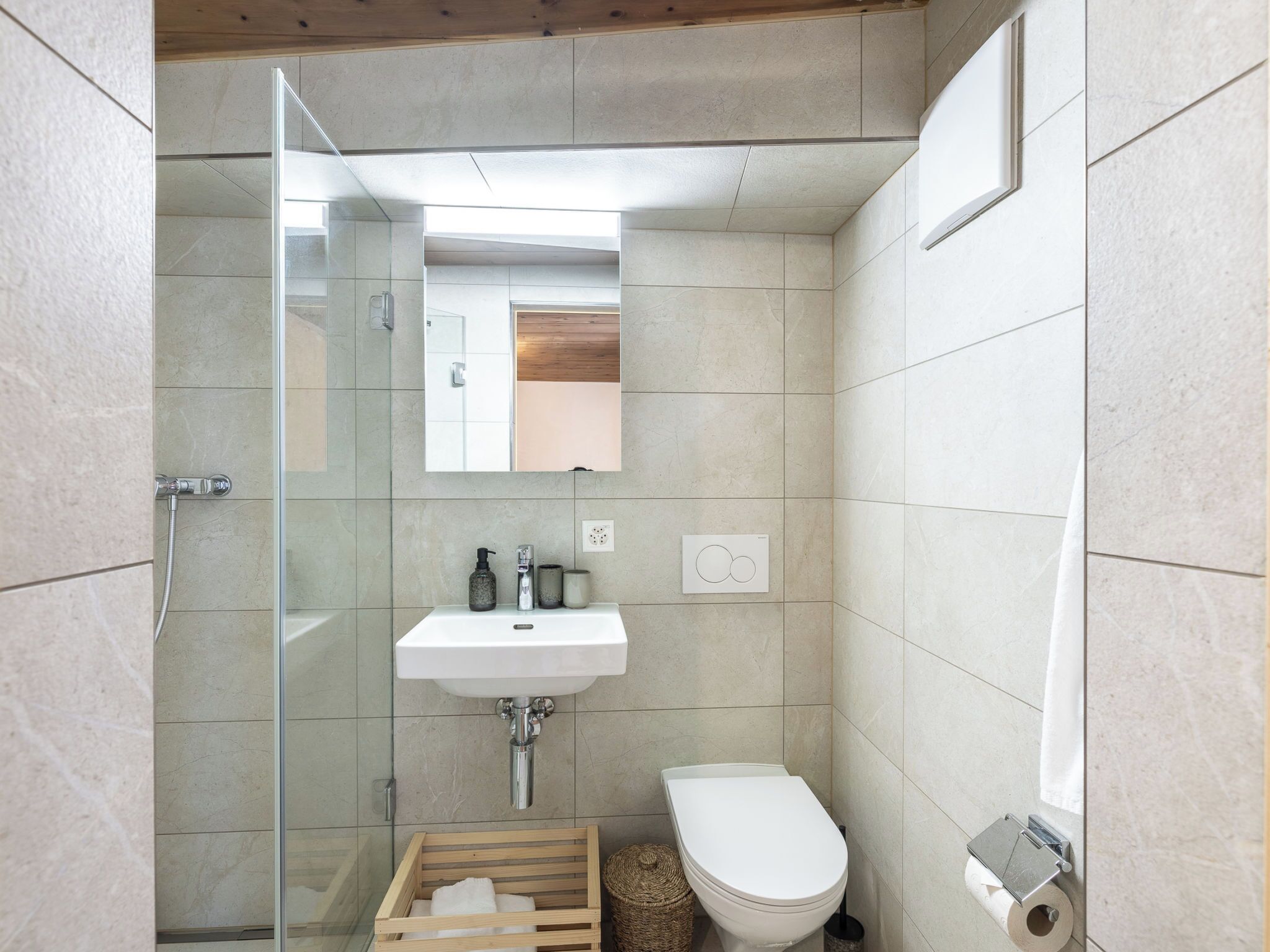 Une salle de bain moderne avec une douche à parois de verre, un lavabo blanc et des toilettes.