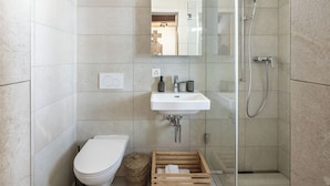 A modern bathroom with a toilet, sink, and glass-enclosed shower.