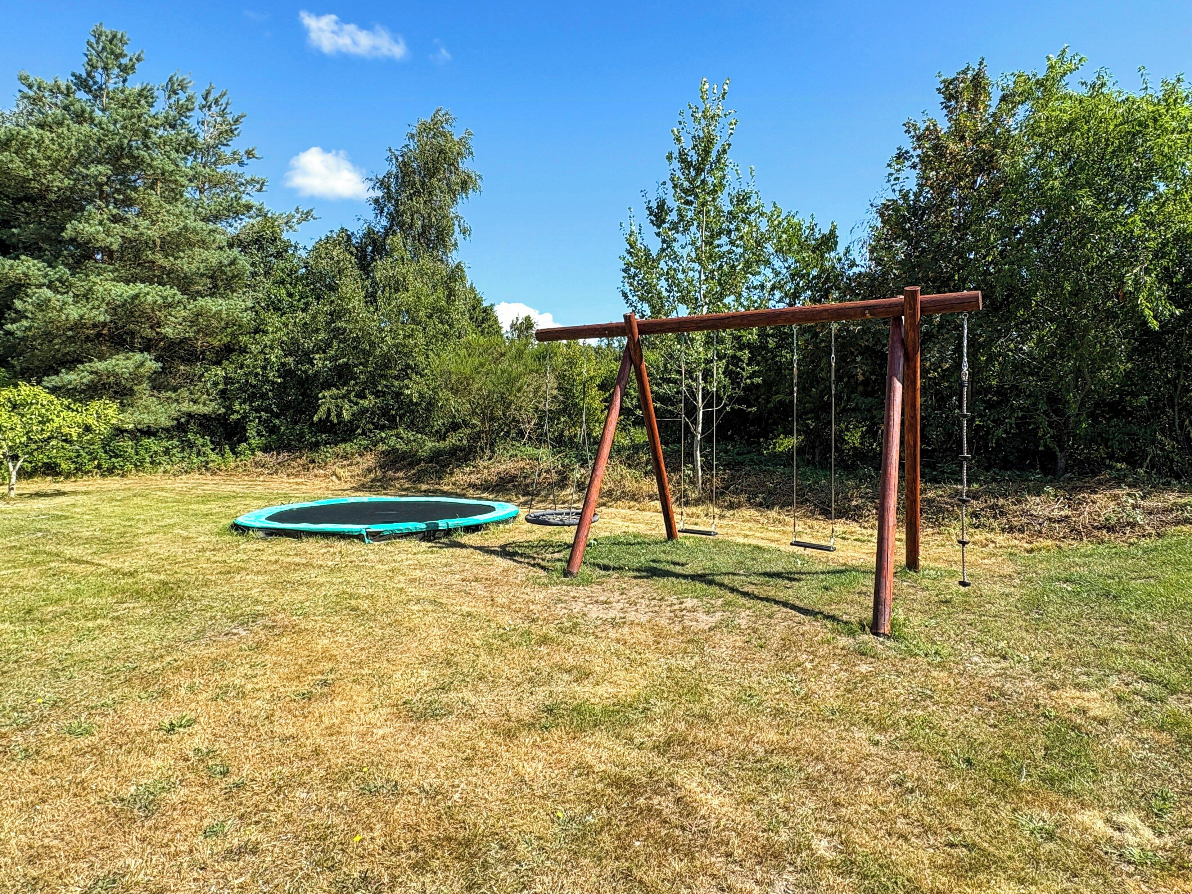 A backyard with a swing set and a trampoline.