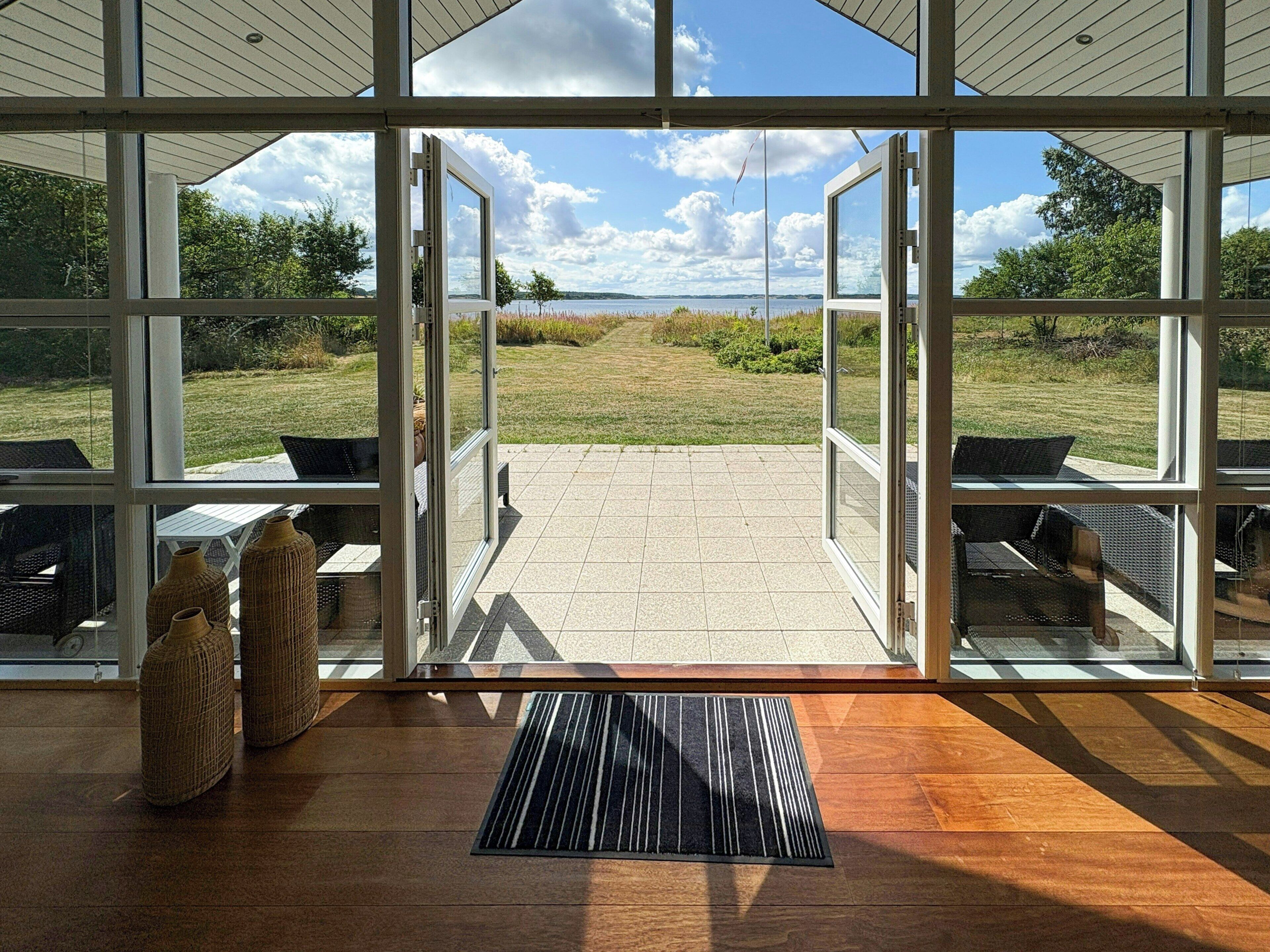 Een modern interieur met grote ramen en uitzicht op een grasveld en water.