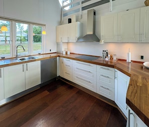 A modern kitchen with white cabinetry, a wooden countertop, and a large window.