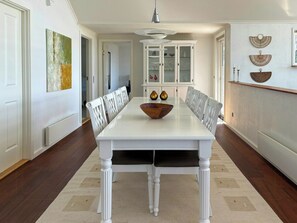 Comedor con mesa blanca, sillas y un cuenco de madera en el centro.