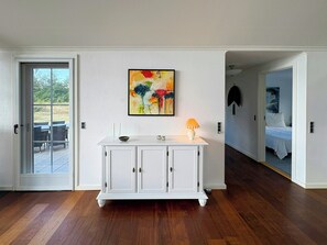 Una habitación con un armario blanco, un cuadro y una cama en la habitación contigua.