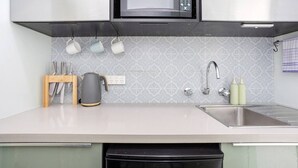 A modern kitchen with a microwave, kettle, sink, and utensils. - Heart of Freo - Charming Heritage Stay (Fremantle)