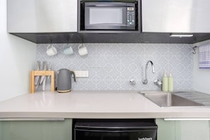 A modern kitchen with a microwave, kettle, sink, and utensils. - Heart of Freo - Charming Heritage Stay (Fremantle)