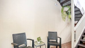 A small outdoor seating area with two chairs and a table, a potted plant, and a staircase. - Heart of Freo - Charming Heritage Stay (Fremantle)