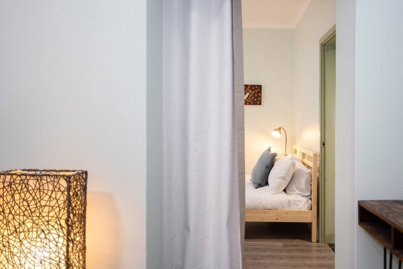 A bedroom with a bed, a bedside lamp, and a wall-mounted artwork.