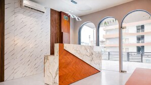 A reception area with a marble reception desk, wooden paneling, and large arched windows. - Axon Business Hotel Sanand Ahmedabad (Ahmedabad)