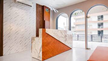 A reception area with a marble reception desk, wooden paneling, and large arched windows.