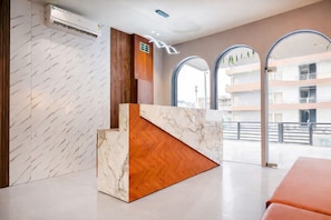 Una zona de recepción con un mostrador de mármol, paneles de madera y amplias ventanas arqueadas.