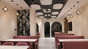 A restaurant interior with booths, tables, and pendant lighting. - Axon Business Hotel Sanand Ahmedabad (Ahmedabad)