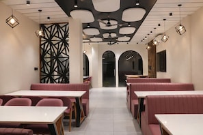 Interior de restaurante con cabinas, mesas e iluminación colgante.