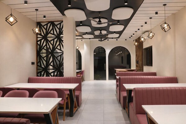 A restaurant interior with booths, tables, and pendant lighting.