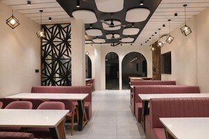 A restaurant interior with booths, tables, and pendant lighting.