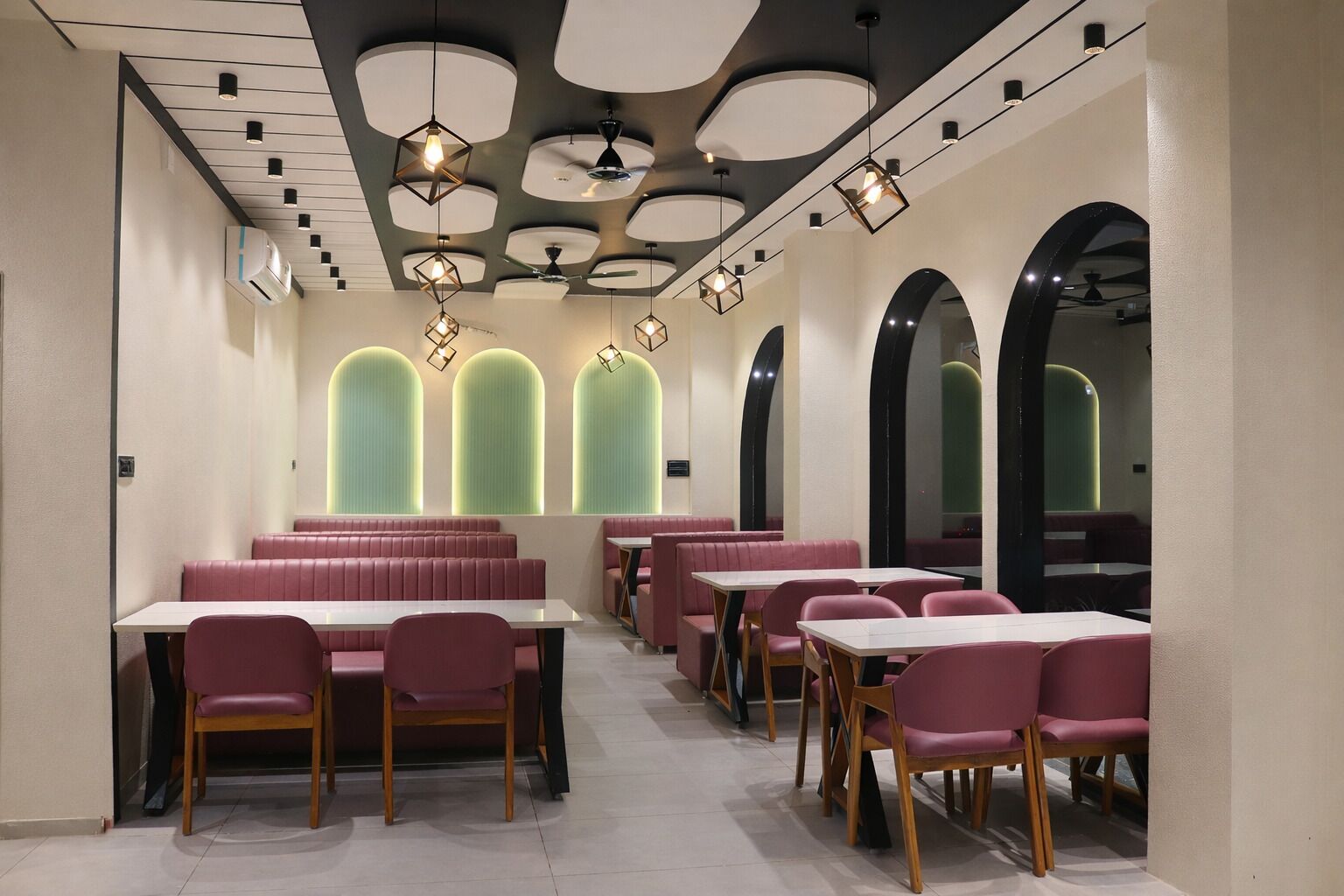 Een modern restaurantinterieur met zitjes, tafels en een uniek plafondontwerp.